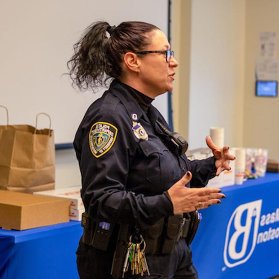 Female police officer speaks at an event at a table.